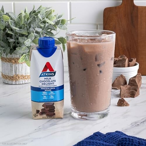 Atkins milk chocolate drink next to a glass of iced chocolate beverage on a marble counter.