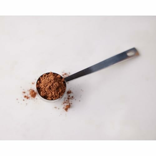 Scoop of cocoa powder on a white surface